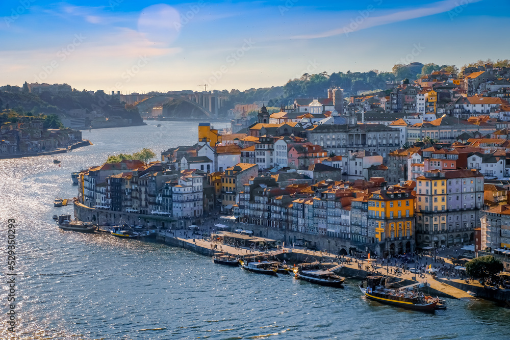 View of Douro River and the city of Porto, Portugal, from a boat; buildings on river bank; bridges and blue sky in background