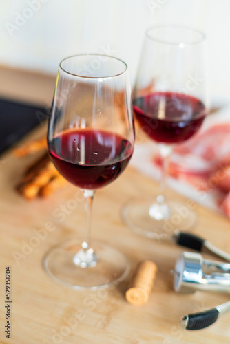 Two glasses of red wine with charcuterie, cheese, grapes and snacks