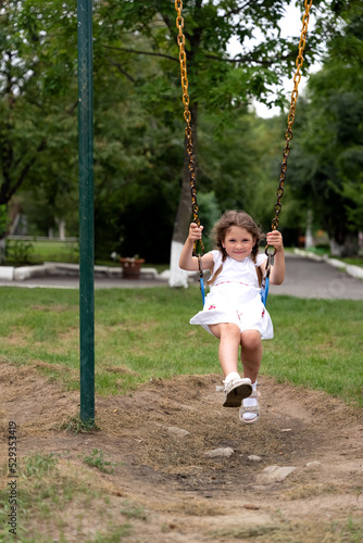 Happy beautiful little girl having fun on a swing. Girl riding on a swing