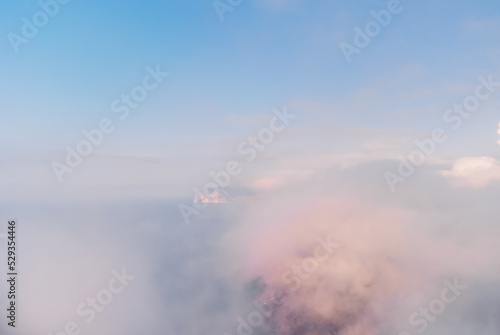 Aerial view. The drone flies over foggy and fluffy clouds. Blue sky sun and sea fog. Abstract aerial nature summer ocean sunset sea and sky background. Vacation, travel and holiday concept