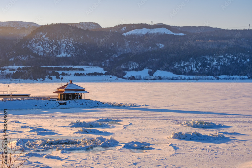 Sunset over the frozen and snow covered Saguenay fjord in Anse Saint Jean village, in Quebec (Canada)