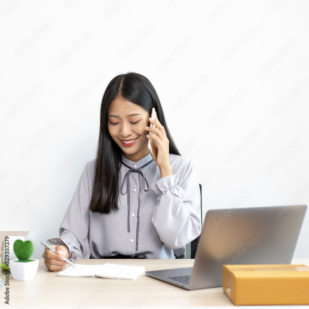 Asian businesswoman is taking online orders from a phone and chatting with customers to confirm their order, Selling products online or doing freelance work at home concept. Asian businesswoman is taking online orders from a phone and chatting with customers to confirm their order, Selling products online or doing freelance work at home concept.