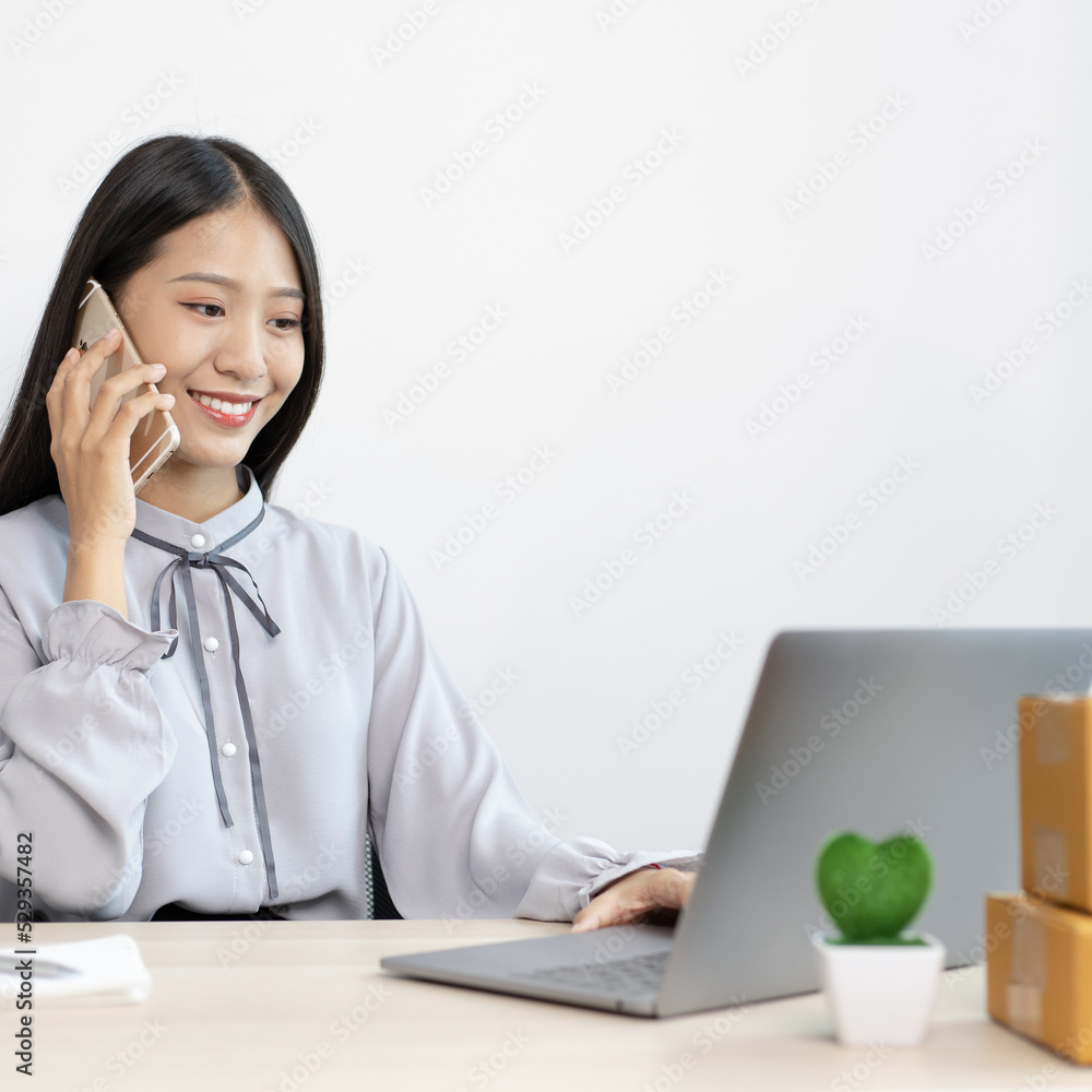 Young Asian women are selling products online and are using mobile phones to chat with customers to confirm orders, Selling products online or doing freelance work at home concept. Young Asian women are selling products online and are using mobile phones to chat with customers to confirm orders, Selling products online or doing freelance work at home concept.