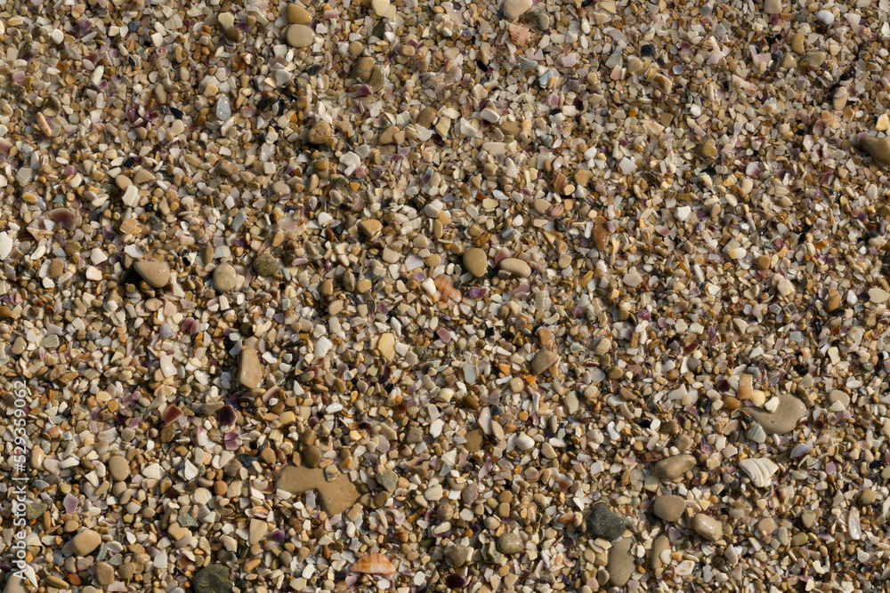 Small pebbles form the background of the sea shore. Coarse multicolor sand. Small pebbles form the background of the sea shore. Coarse multicolor sand.