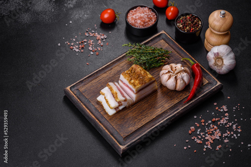 Smoked lard, bacon, half a piece, on a wooden dark cutting board