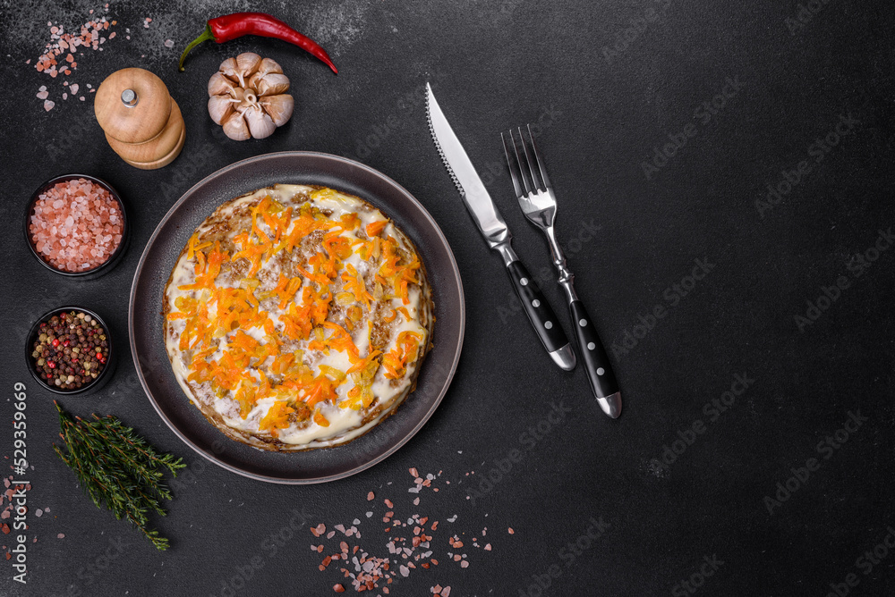 Delicious fresh liver cake with mayonnaise and carrots on a black plate against a dark concrete background Delicious fresh liver cake with mayonnaise and carrots on a black plate against a dark concrete background