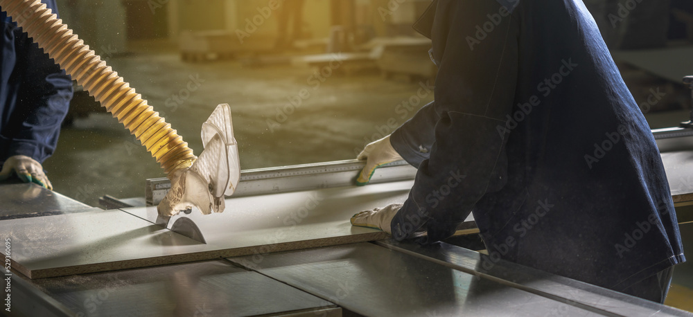 Carpenter in the workshop saws chipboard and a wooden board with a circular saw on the machine. Carpenter in the workshop saws chipboard and a wooden board with a circular saw on the machine.