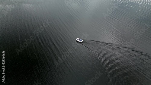 Drone Aerial footage of a small boat on Derwentwater, Keswick, a calm lake with river boats and a stormy sky. Surrounded by mountain's, hills and lush woodland. photo