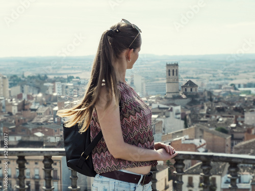 Fototapeta Adult tourist girl with long blonde hair looks at Tarrega city (Catalonia, Spain) from the observation deck