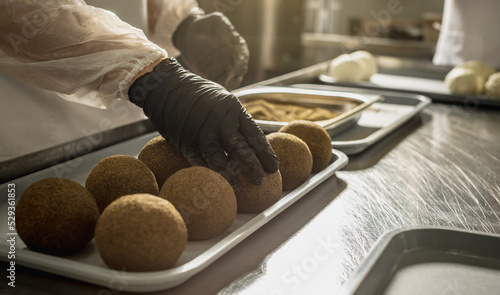 Farmer in black gloves sprinkle black pepper on a cheese ball. The production process of Belper knolle cheese photo