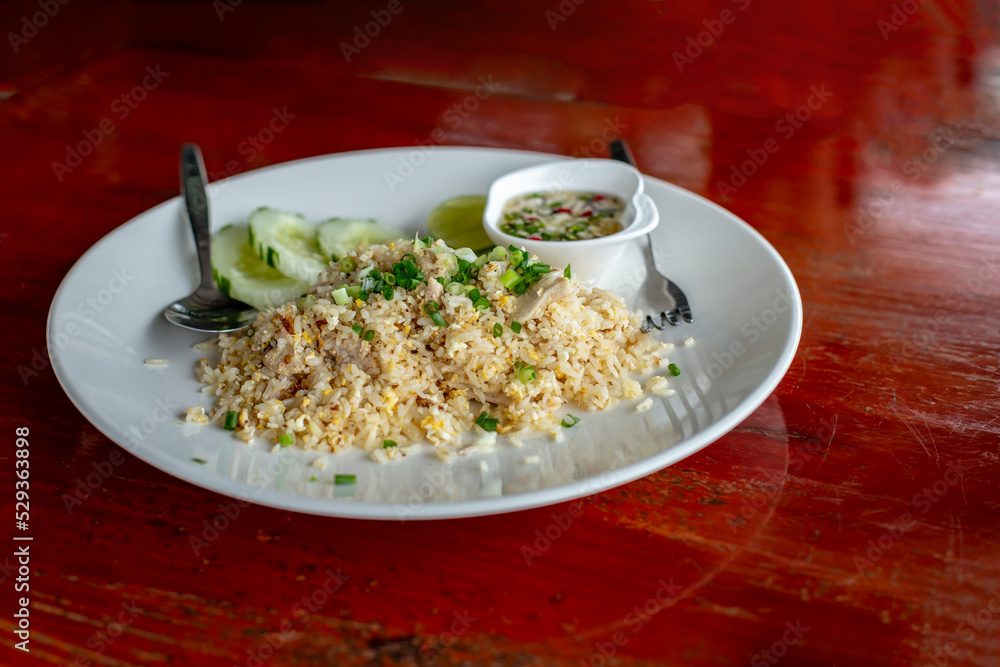 Pork fried rice on a white plate on a wooden table