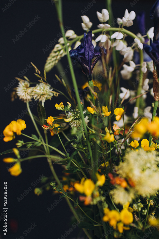 Beautiful bouqet of wild flowers on black background. Stylish flower composition. Selective focus, film grain