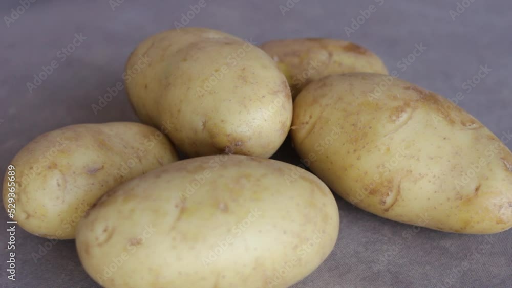 Person's Hand Put Five Raw Potatoes On The Table. - close up Person's Hand Put Five Raw Potatoes On The Table. - close up
