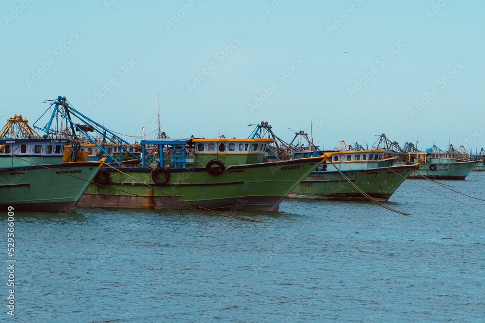 Fishing boats floating on the calm blue sea water in the Pamban island in Rameshwaram, Tamilnadu, India. Monsoon season fishing in India. Fishing boats in the harbor.