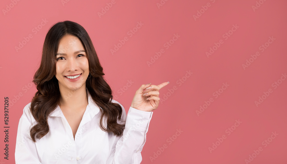 Portrait asian woman with long hair wearing a white shirt pointing to pink background. isolated space. Portrait asian woman with long hair wearing a white shirt pointing to pink background. isolated space.