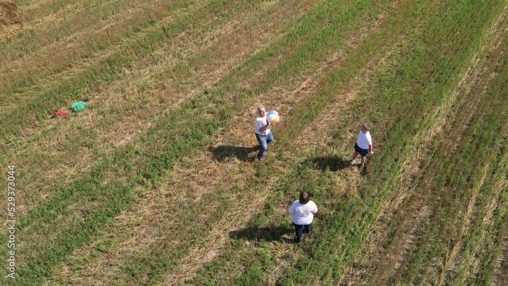 Funny happy family playing ball outdoors, aerial view. A married couple with their son are having fun on a mowed wheat field, enjoying the beautiful clean nature. Happy family concept. UHD 4K. Funny happy family playing ball outdoors, aerial view. A married couple with their son are having fun on a mowed wheat field, enjoying the beautiful clean nature. Happy family concept. UHD 4K.