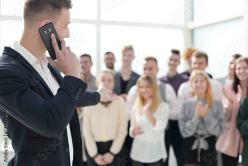 business man with smartphone pointing at a group of young people.