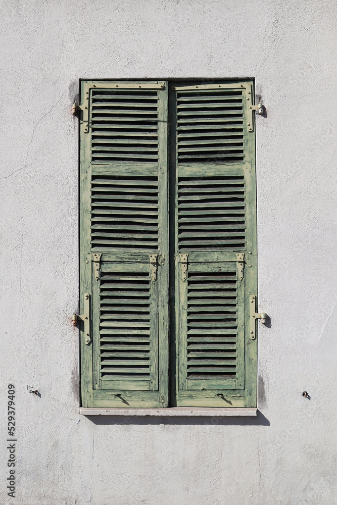 Typical facade in the south of France, on the French Riviera, windows with colored shutters.