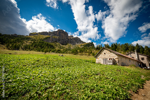 landscape with clouds over the mountains dolomiti, with blue sky an house and green trees in Italy