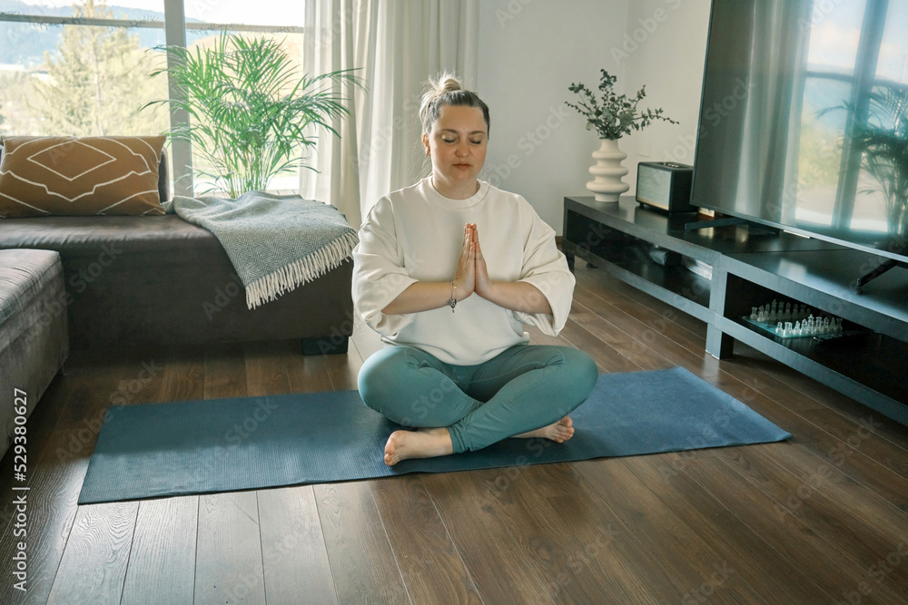 Woman doing online yoga at home. Female teaches asana in video conference. Health care, authenticity, sense of balance and calmness.