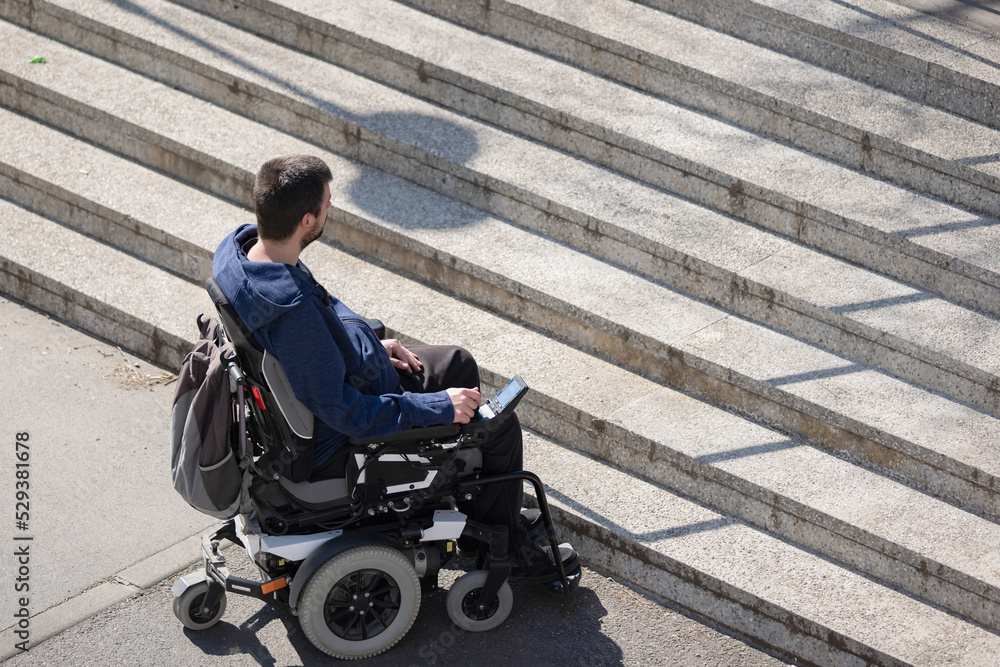 Person with disability on electric wheelchair stopping at the bottom of