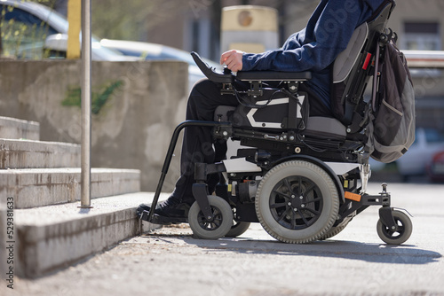 Man with disability on wheelchair stopped in front of staircase, raising awareness of architectural barriers and accessibility issues