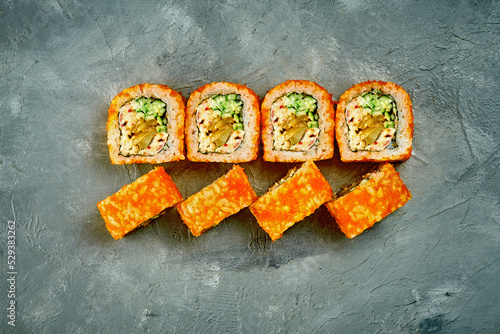 Sushi roll with eel and cucumber on gray background. Selective focus, noise added in post-production
