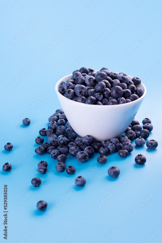 Beautiful fresh blueberries in a white bowl on a blue background.Vegan and vegetarian concept. Summer healthy food.