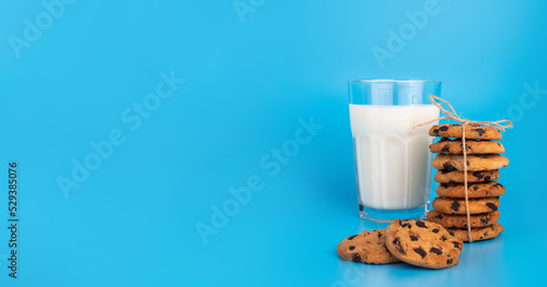 Glass of fresh milk and brown school chokolate cookies on blue background photo