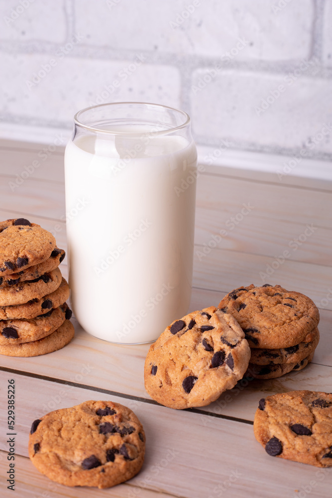 Flatlay an after school snack of chocolate chip cookies and an glass cup of milk. The cookies with chocolate drops and on a rustic wood kitchen table, with copy space. yummy and tasty Flatlay an after school snack of chocolate chip cookies and an glass cup of milk. The cookies with chocolate drops and on a rustic wood kitchen table, with copy space. yummy and tasty