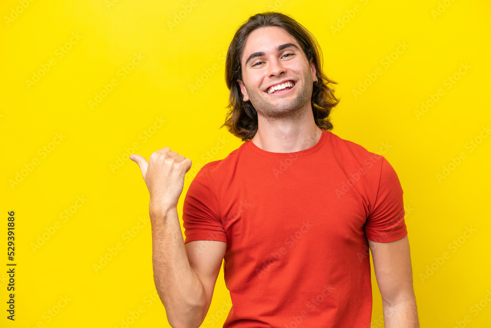 Caucasian handsome man isolated on yellow background pointing to the side to present a product Caucasian handsome man isolated on yellow background pointing to the side to present a product