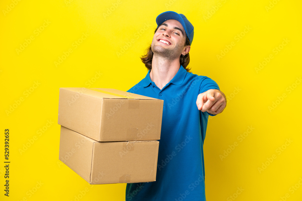 Delivery handsome man isolated on yellow background pointing front with happy expression Delivery handsome man isolated on yellow background pointing front with happy expression