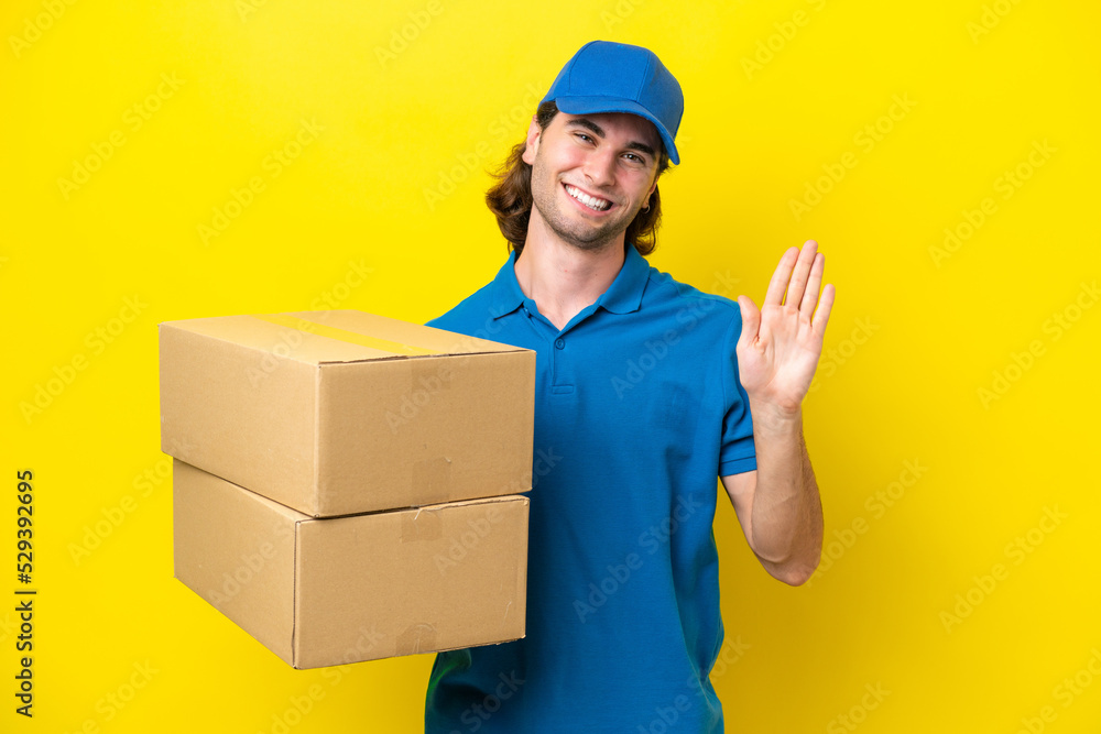 Delivery handsome man isolated on yellow background saluting with hand with happy expression Delivery handsome man isolated on yellow background saluting with hand with happy expression