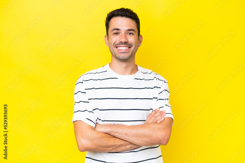 Young handsome man over isolated yellow background keeping the arms crossed in frontal position Young handsome man over isolated yellow background keeping the arms crossed in frontal position