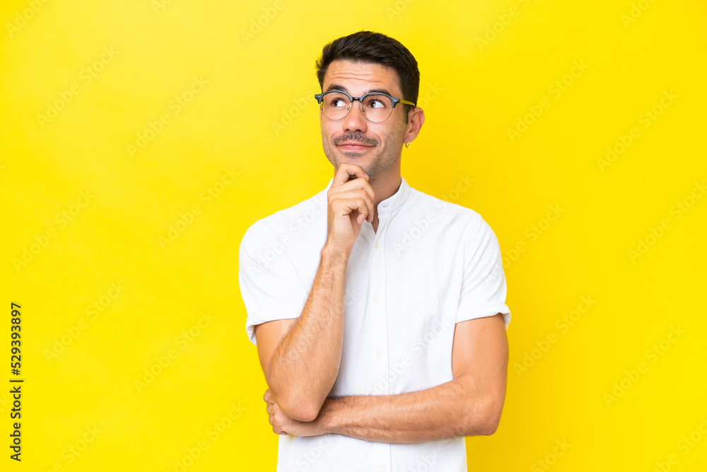 Young handsome man over isolated yellow background thinking an idea while looking up Young handsome man over isolated yellow background thinking an idea while looking up