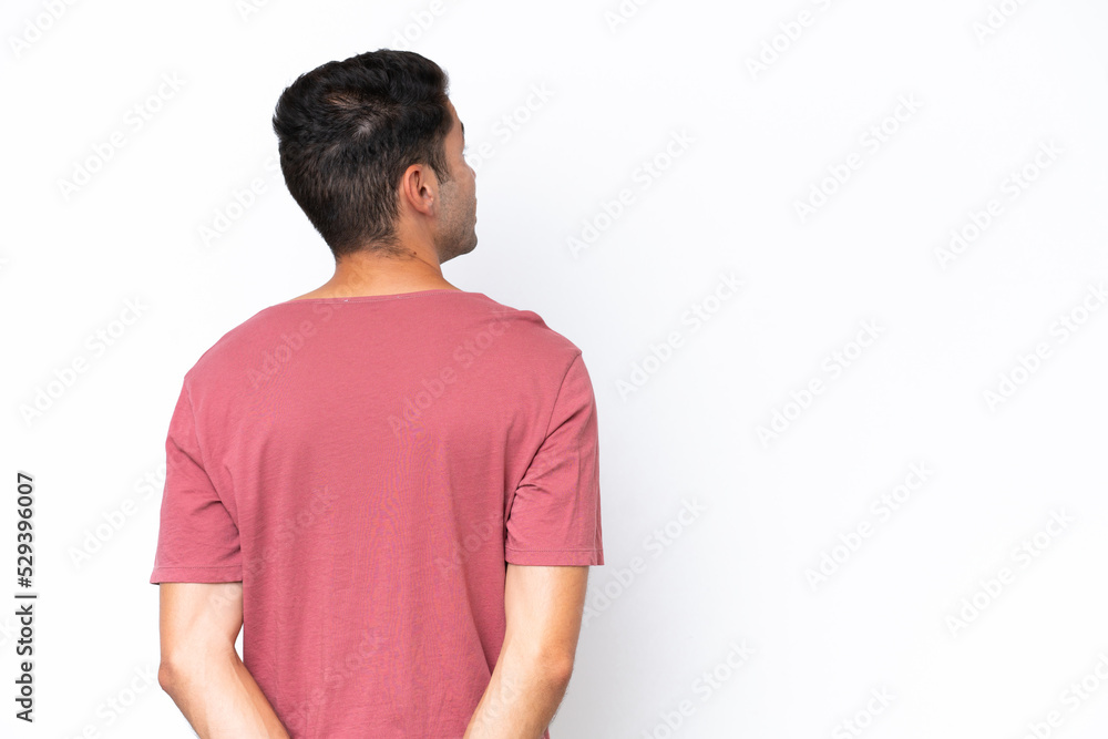 Young handsome man over isolated white background in back position and looking back Young handsome man over isolated white background in back position and looking back