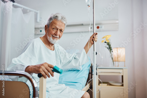 Smiling elderly man recovering at intensive care unit in hospital and looking at camera.
