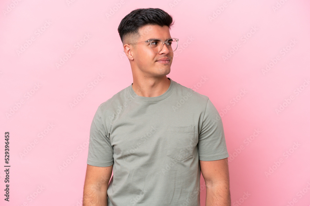 Young caucasian handsome man isolated on pink background having doubts while looking side Young caucasian handsome man isolated on pink background having doubts while looking side