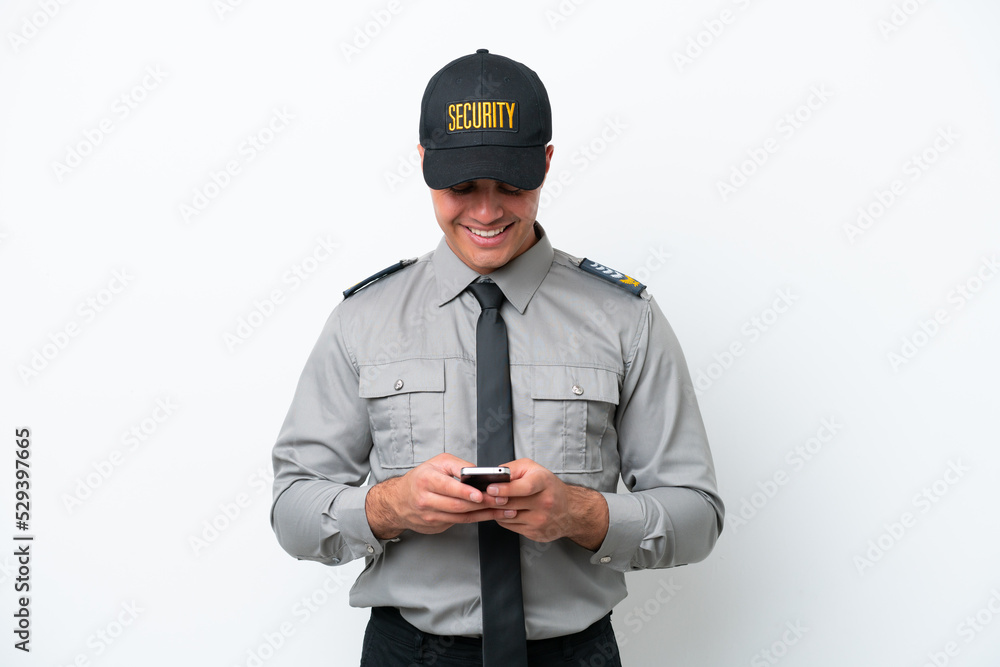 Young caucasian security man isolated on white background sending a message with the mobile Young caucasian security man isolated on white background sending a message with the mobile
