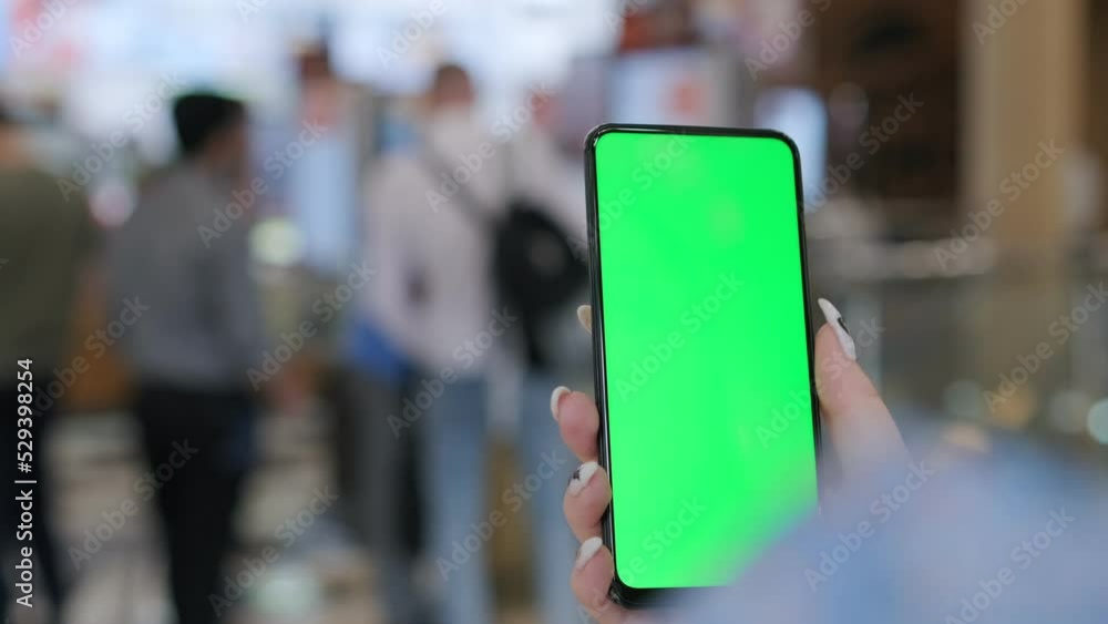 Back view of brunette holding chroma key green screen smartphone watching content. Hand holds mobile phone and scrolls up web page . Gadgets and contemporary people concept. Use online payment Back view of brunette holding chroma key green screen smartphone watching content. Hand holds mobile phone and scrolls up web page . Gadgets and contemporary people concept. Use online payment