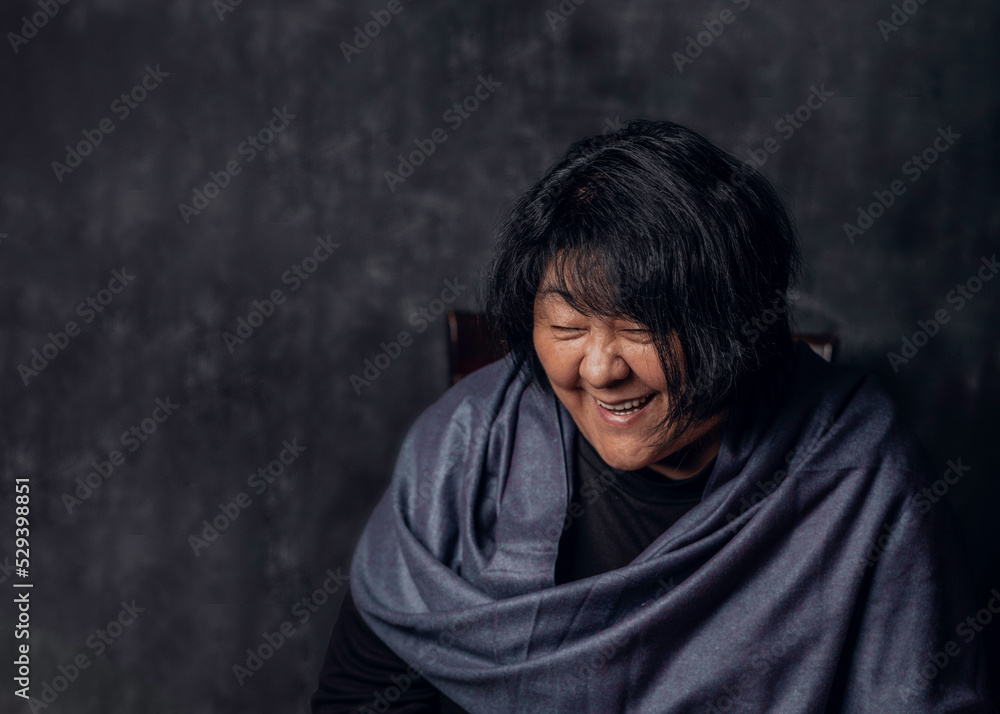 Laughing mature middle aged Asian woman joyful and cheerful. Asian woman in her early fifties isolated on dark background. Laughing mature middle aged Asian woman joyful and cheerful. Asian woman in her early fifties isolated on dark background.
