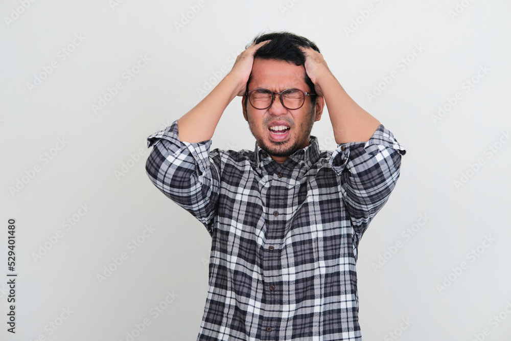 Asian man showing stress expression with his hand grabbing hair Asian man showing stress expression with his hand grabbing hair