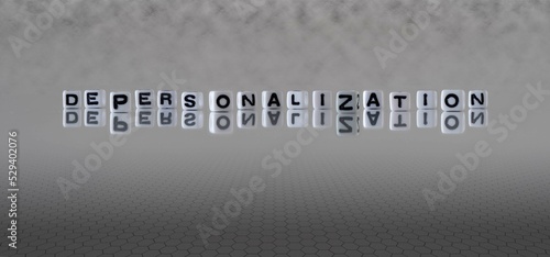 depersonalization word or concept represented by black and white letter cubes on a grey horizon background stretching to infinity photo