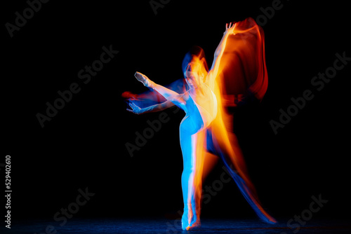 Flexible and beautiful girl, ballet dancer in motion over dark background in mixed neon light. Grace, art, flexibility, inspiration concept.