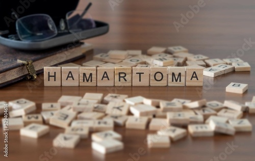 hamartoma word or concept represented by wooden letter tiles on a wooden table with glasses and a book photo