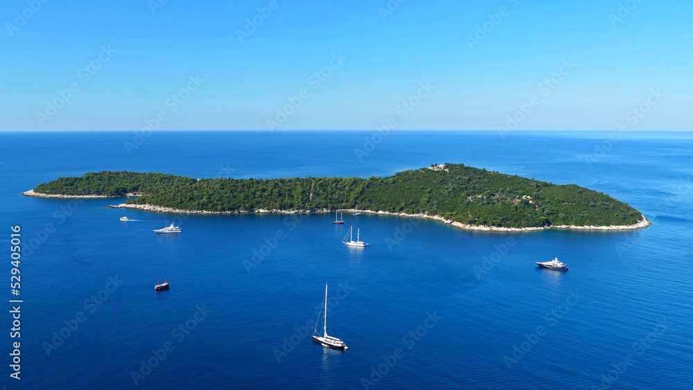 island in ocean with boat and yatch