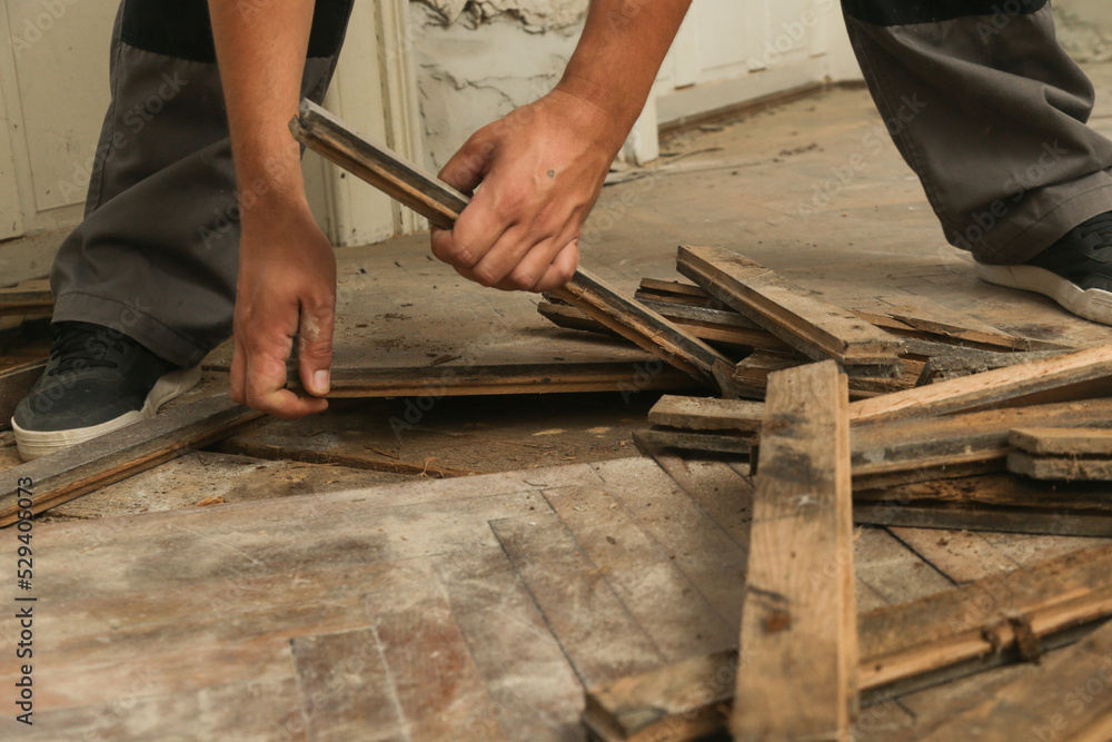 Home improvement. Construction worker or handyman is removing old wooden parquet flooring using crowbar tool. Old wooden floor renovation. Home improvement. Construction worker or handyman is removing old wooden parquet flooring using crowbar tool. Old wooden floor renovation.