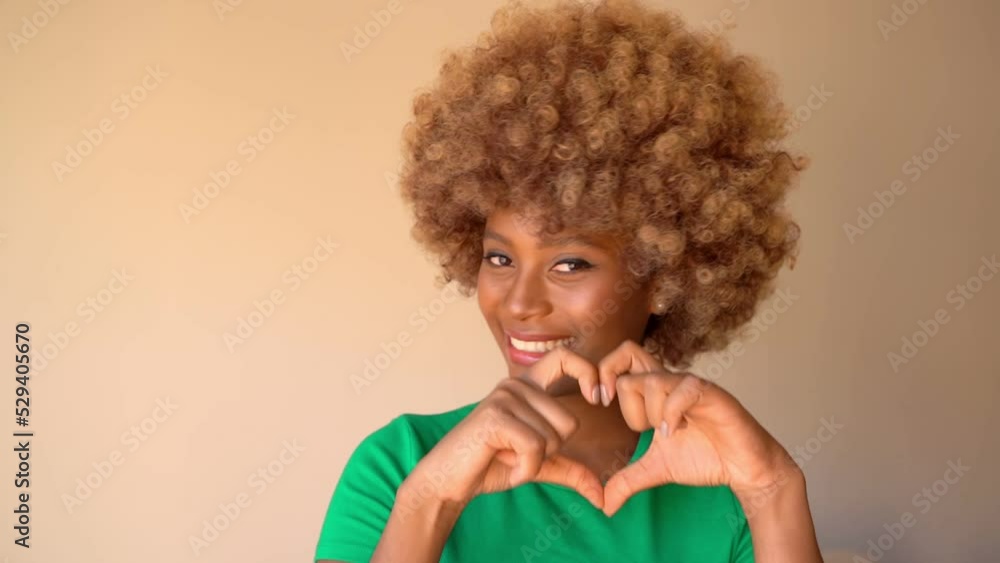 beautiful smiling dark-skinned woman in green t-shirt playfully and flirting shows air kiss and heart shape with hands. Happy positive love romantic emotions. Light beige background video footage beautiful smiling dark-skinned woman in green t-shirt playfully and flirting shows air kiss and heart shape with hands. Happy positive love romantic emotions. Light beige background video footage