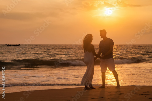 Adult lovely family couple holding hands relaxing at ocean sunset background. Man and woman in casual clothes, walking together sandy beach outdoor. Travel vacation concept. Copy text space