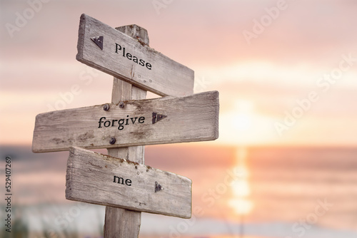 please forgive me text quote engraved on wooden signpost outdoors on the beach with sunset theme. photo